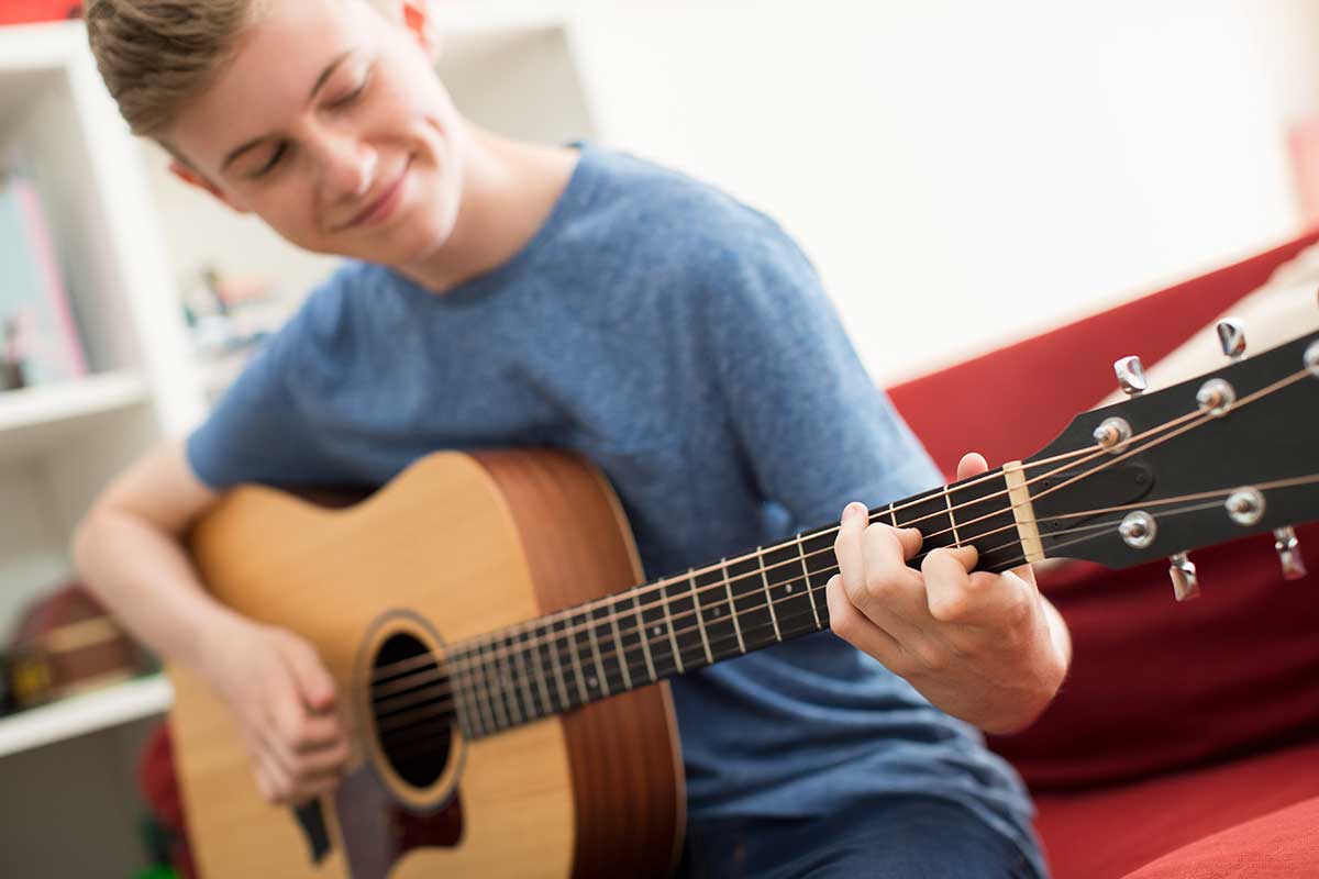 Lächelnder Jugendlicher spielt Gitarre