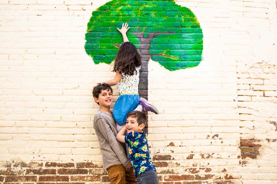 3 Kinder spielen an einer Mauer